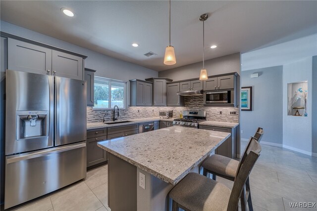 kitchen with under cabinet range hood, stainless steel appliances, tasteful backsplash, and a sink