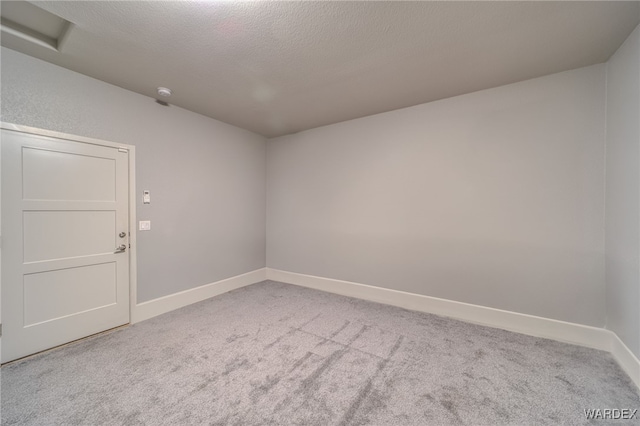 carpeted spare room with a textured ceiling and baseboards