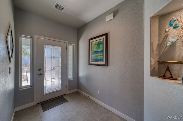 tiled foyer entrance featuring visible vents and baseboards