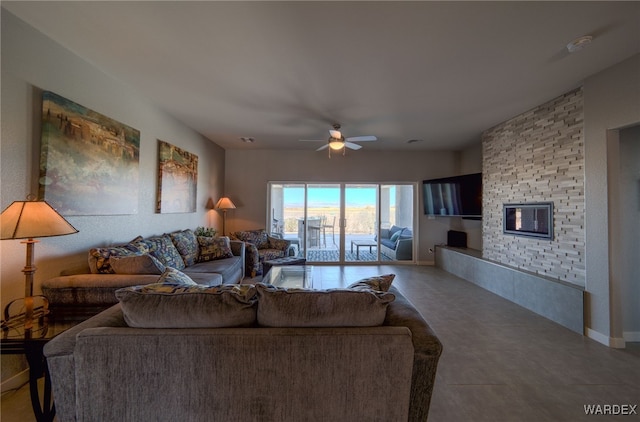 living room with baseboards, a large fireplace, and a ceiling fan