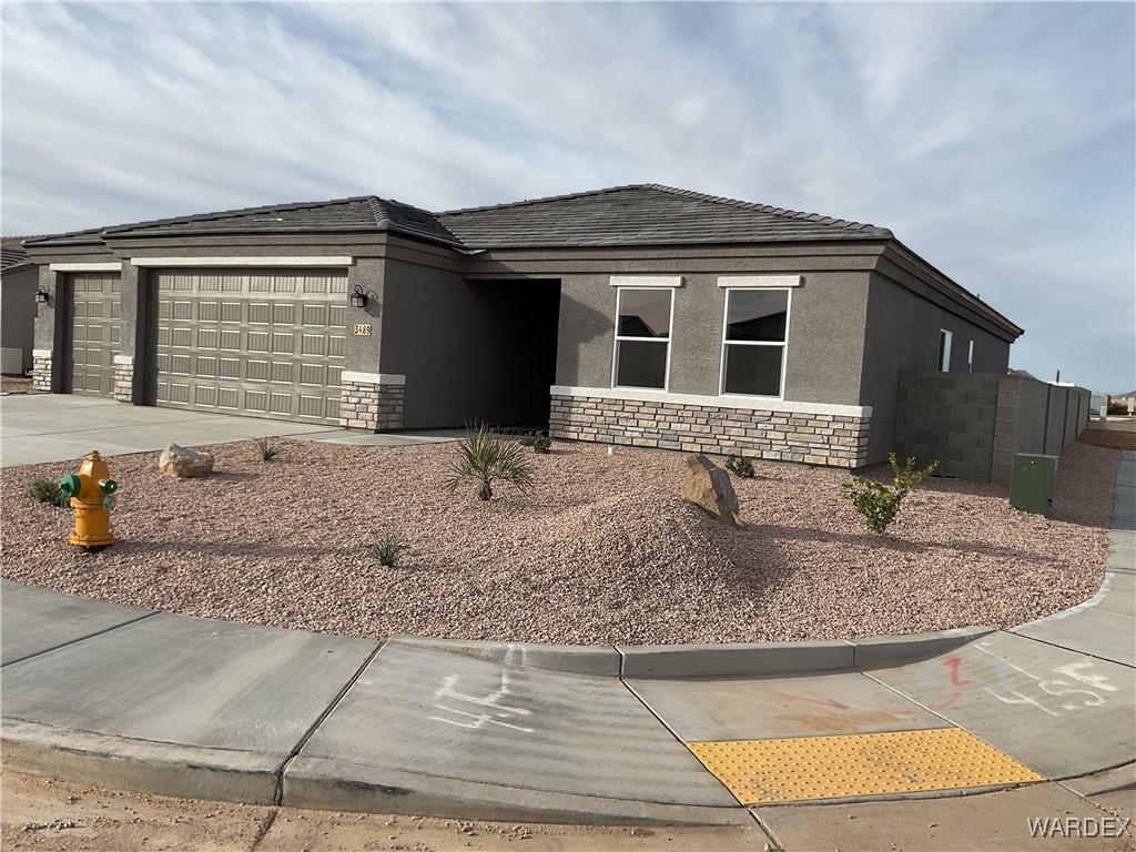 view of front facade with an attached garage, stone siding, driveway, and stucco siding