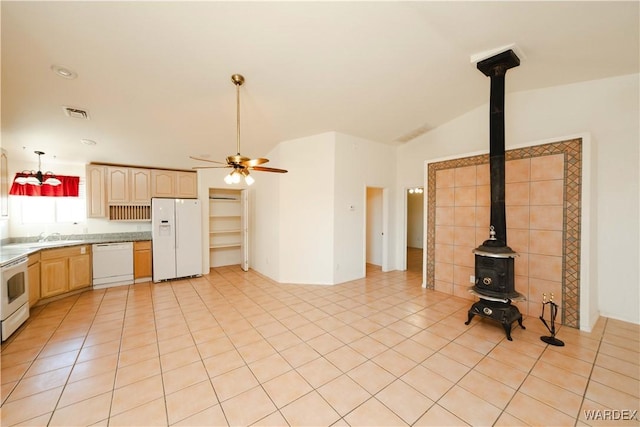 kitchen with vaulted ceiling, a wood stove, white appliances, hanging light fixtures, and ceiling fan