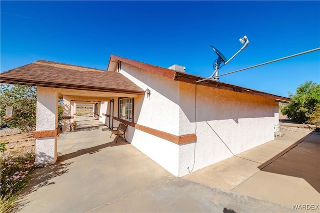 view of side of property featuring stucco siding and a patio area