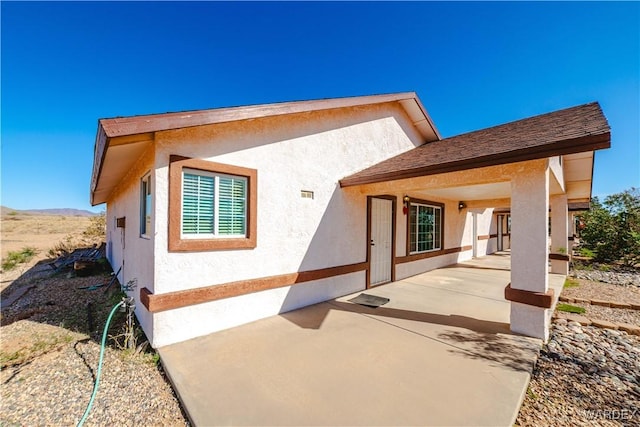back of property with a patio and stucco siding