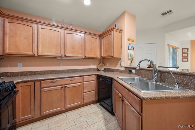 kitchen with dark countertops, a sink, a peninsula, and black appliances