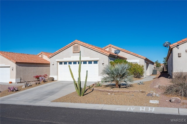 view of front of property featuring driveway, an attached garage, a tiled roof, and stucco siding