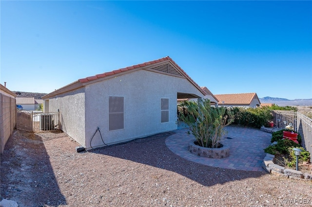 view of side of property with a fenced backyard, a patio area, a mountain view, central AC, and stucco siding