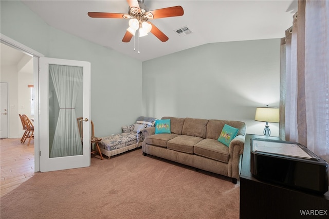 carpeted living room featuring lofted ceiling, visible vents, and a ceiling fan