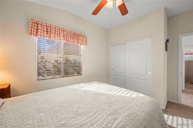 carpeted bedroom featuring a ceiling fan, lofted ceiling, a closet, and baseboards