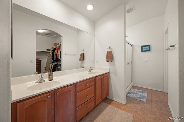 full bath featuring double vanity, tile patterned flooring, a sink, and a walk in closet