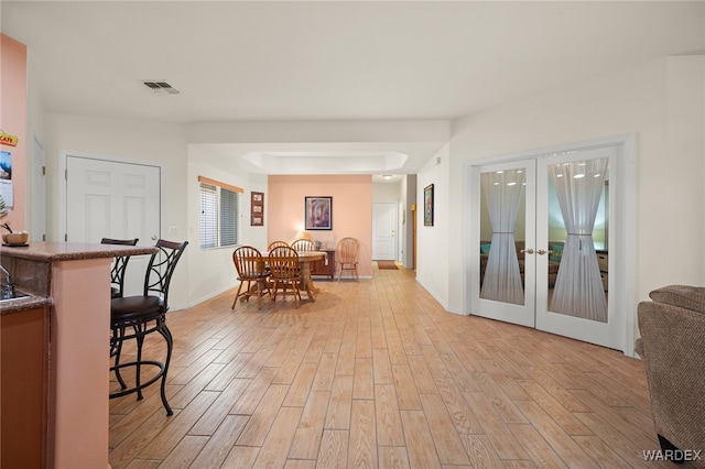 interior space featuring light wood-style flooring, visible vents, baseboards, and french doors