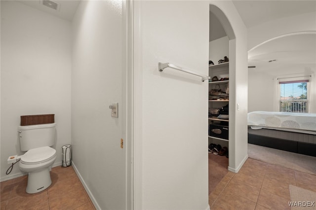 bathroom with toilet, baseboards, and tile patterned floors