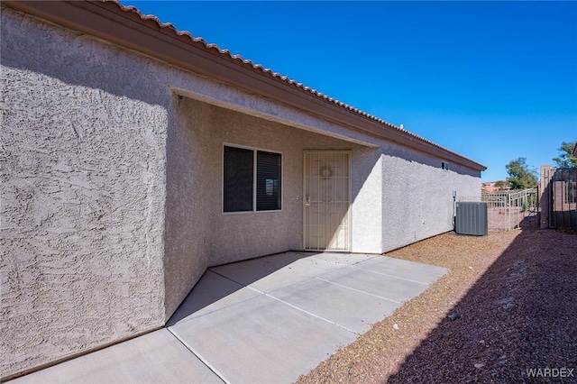 rear view of property featuring a tile roof, stucco siding, a patio area, central AC, and fence