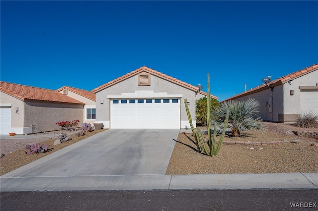 view of front of house featuring an attached garage, a tiled roof, concrete driveway, and stucco siding