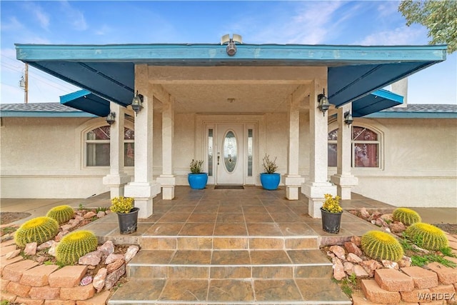 entrance to property with a porch and stucco siding