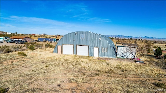 view of outdoor structure featuring driveway, an outdoor structure, and a mountain view