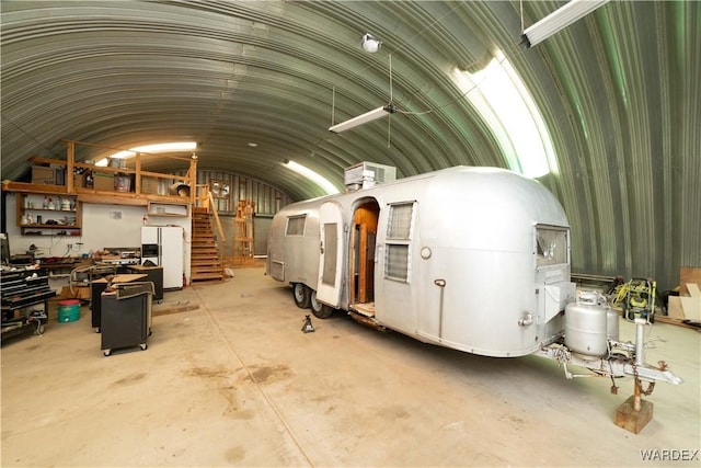 misc room featuring concrete flooring, lofted ceiling, and stairway