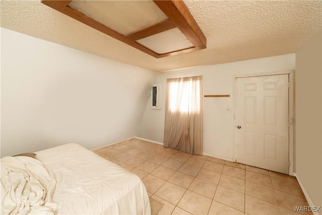 bedroom with attic access, baseboards, a textured ceiling, and light tile patterned flooring