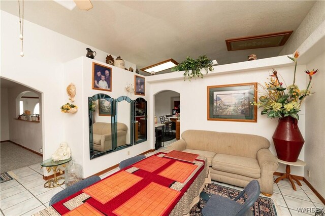 living room with arched walkways, baseboards, and light tile patterned floors