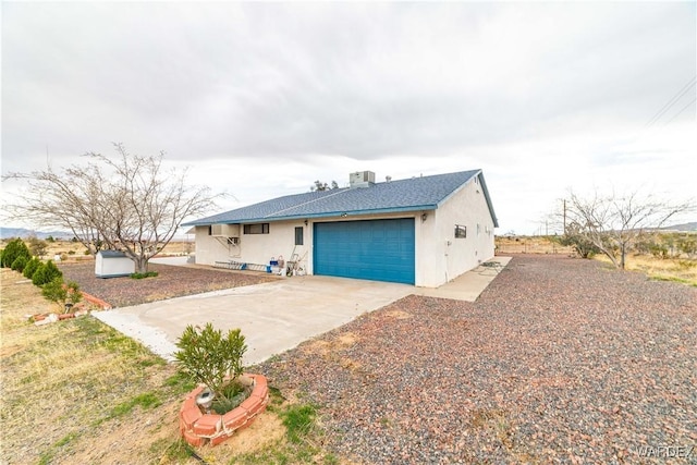 view of front of house with a garage, cooling unit, concrete driveway, and stucco siding