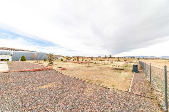 view of yard with fence and a rural view