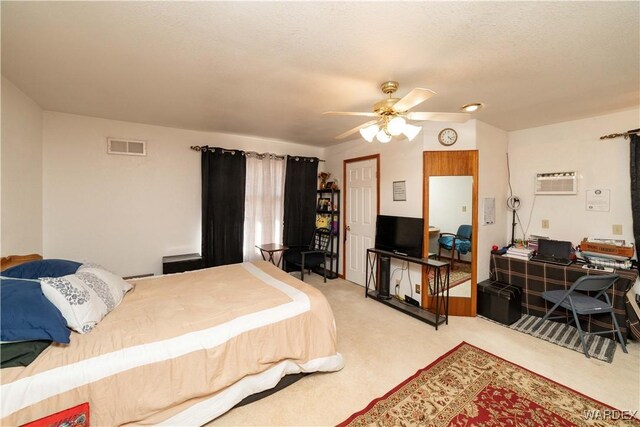 bedroom with a textured ceiling, light carpet, visible vents, a ceiling fan, and an AC wall unit