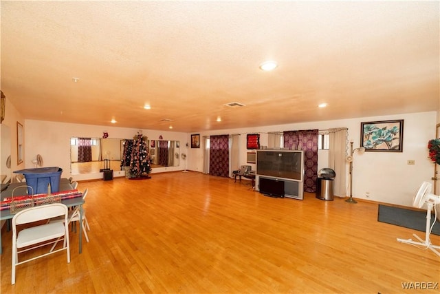 interior space featuring light wood-style floors, baseboards, visible vents, and a textured ceiling