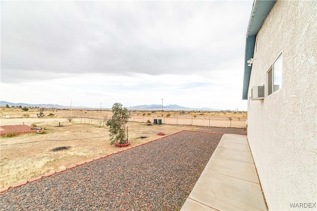 view of yard featuring fence, a mountain view, and a rural view