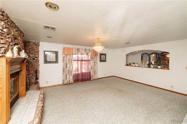 unfurnished living room with baseboards, visible vents, light colored carpet, a textured ceiling, and a fireplace