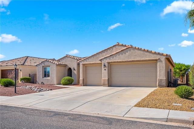 mediterranean / spanish house featuring a garage, a tiled roof, concrete driveway, and stucco siding