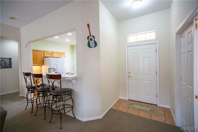 foyer entrance featuring light carpet, light tile patterned floors, baseboards, arched walkways, and recessed lighting