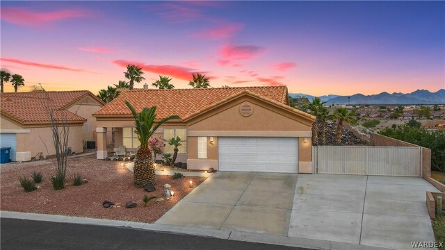 view of front of house with stucco siding, concrete driveway, a mountain view, a garage, and a tiled roof