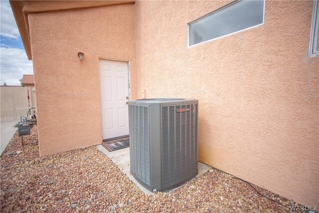 exterior details featuring central AC, gas meter, and stucco siding