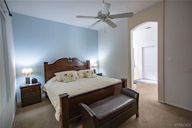 bedroom with baseboards, visible vents, arched walkways, a ceiling fan, and light colored carpet