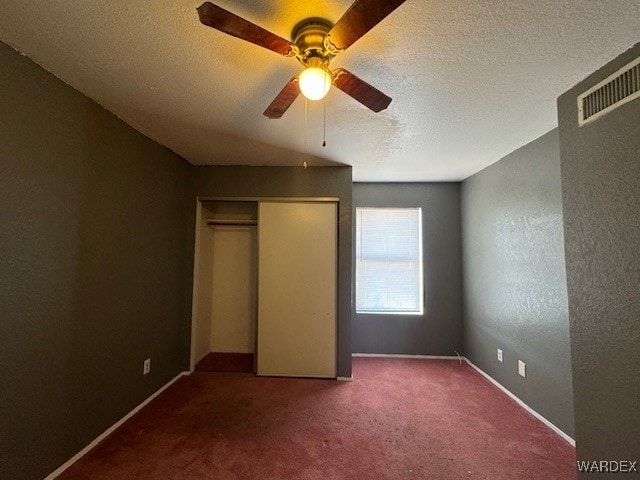 unfurnished bedroom with visible vents, a textured ceiling, a closet, and carpet flooring