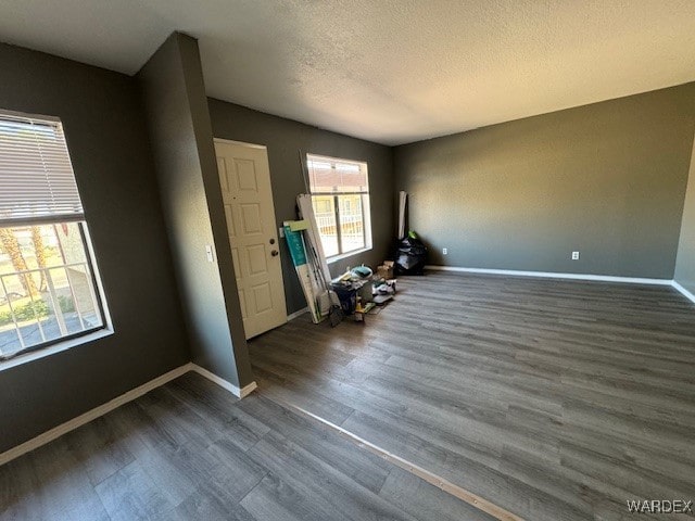 empty room featuring wood finished floors, a textured ceiling, and baseboards