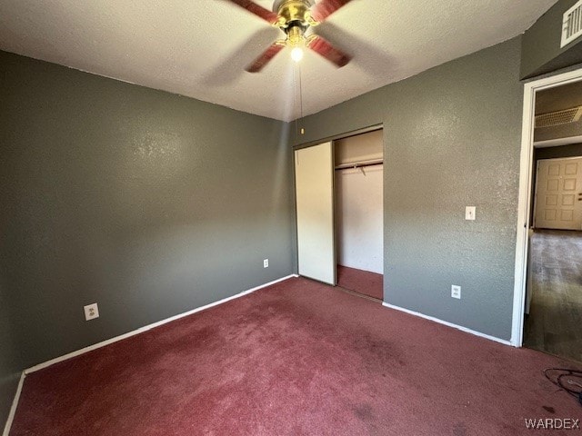 unfurnished bedroom featuring visible vents, baseboards, a ceiling fan, dark carpet, and a closet