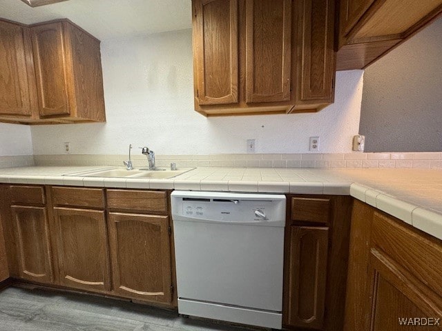 kitchen featuring dishwasher, a sink, and light countertops