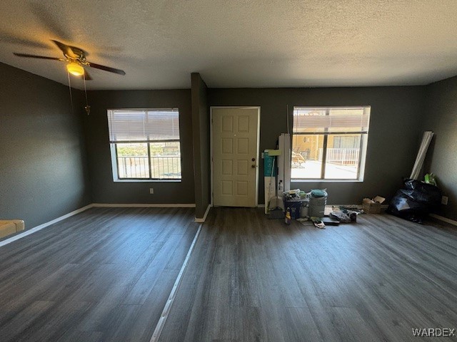 interior space with baseboards, a textured ceiling, dark wood-style floors, and ceiling fan