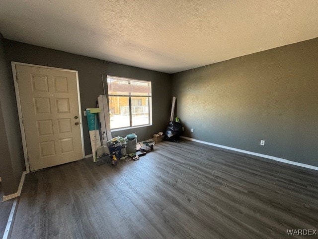 interior space featuring baseboards, a textured ceiling, and dark wood-type flooring