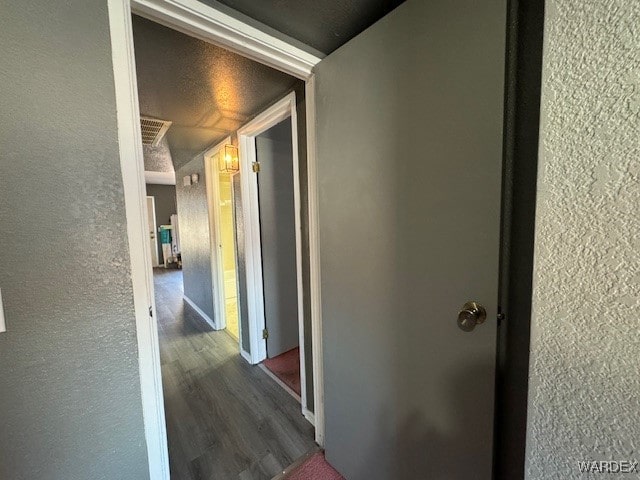corridor featuring wood finished floors and a textured wall