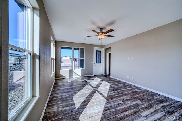 unfurnished room featuring a ceiling fan, baseboards, and dark wood-style flooring