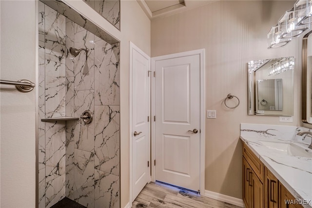 bathroom featuring wood finished floors, a marble finish shower, vanity, and baseboards