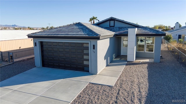 ranch-style home with an attached garage, driveway, fence, and stucco siding