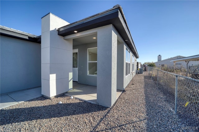 view of side of property with a patio area, fence, and stucco siding