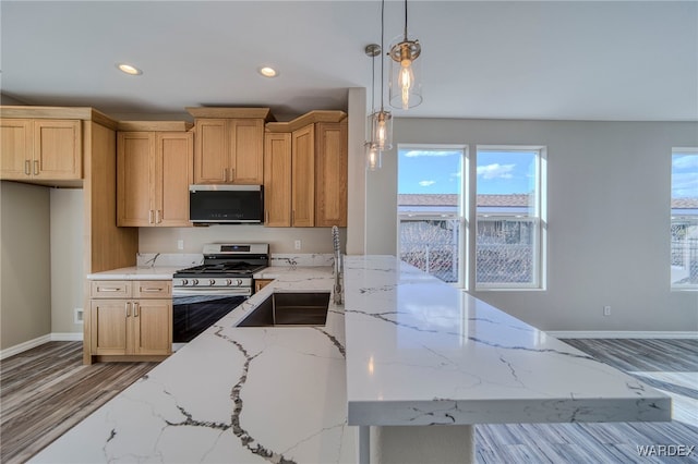 kitchen featuring baseboards, decorative light fixtures, light stone countertops, stainless steel gas range, and recessed lighting