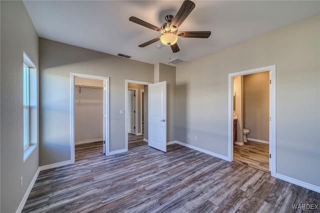 unfurnished bedroom with dark wood-style floors, a closet, visible vents, and baseboards