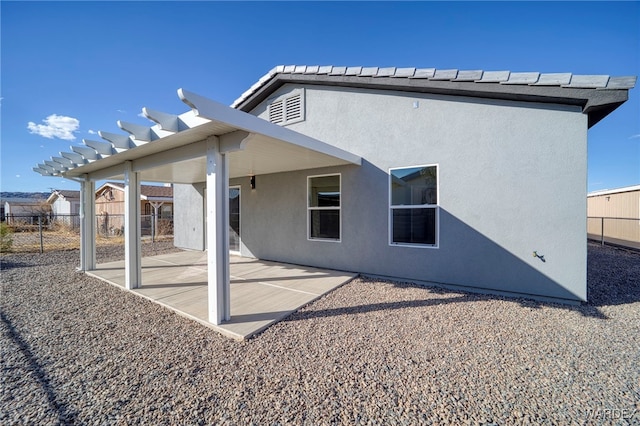 rear view of property featuring a patio area, fence, and stucco siding