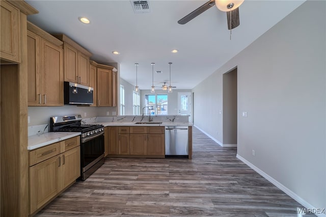 kitchen featuring visible vents, decorative light fixtures, stainless steel appliances, light countertops, and a sink