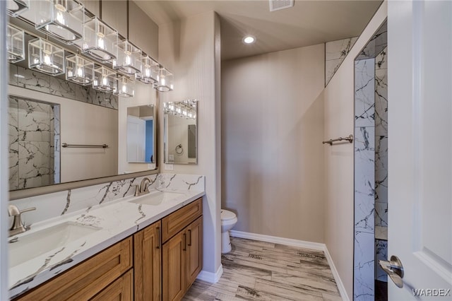 bathroom featuring wood finished floors, a sink, toilet, and double vanity